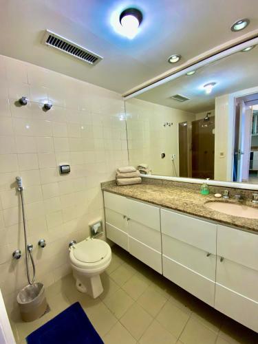 a bathroom with a toilet and a sink and a mirror at Ondina Apart Hotel Residences in Salvador