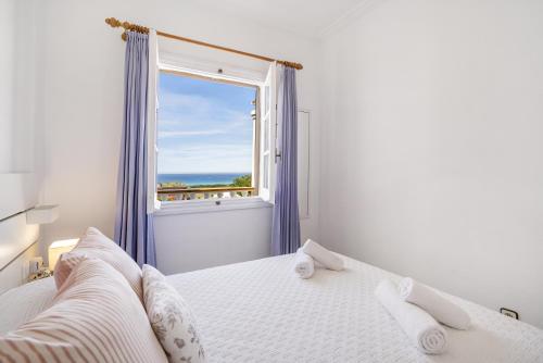 a white bedroom with a window and a bed at Can Poriol in Alaior