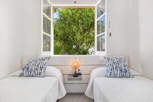 two beds in a room with two windows at Can Poriol in Alaior