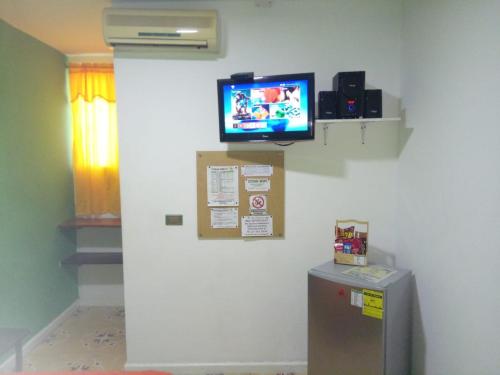 a room with a tv on a wall with a refrigerator at Hotel Nogales Riohacha in Ríohacha