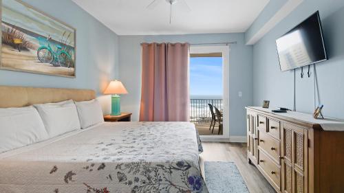 a bedroom with a bed and a television and a balcony at Some Beach Some Where at Laketown Wharf #825 by Nautical Properties in Panama City Beach