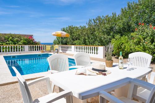a white table and chairs next to a swimming pool at Can Poriol in Alaior