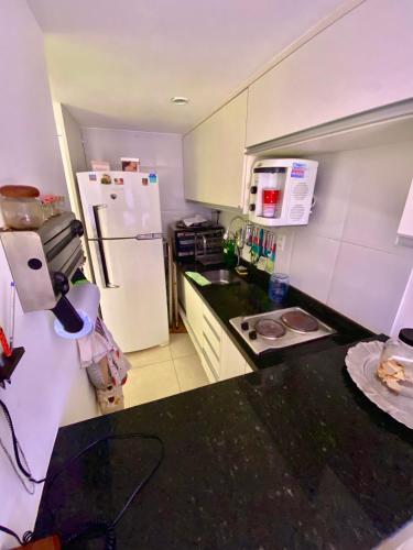 a kitchen with a white refrigerator and a black counter top at Ondina Apart Hotel Residences in Salvador