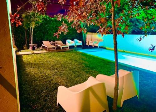 a garden with chairs and a tree next to a pool at Portugal Holidays Villa in Barcelos