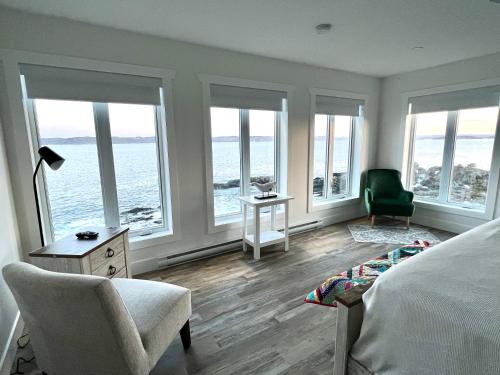 a bedroom with windows and a bed and a chair at The View suites and breakfast in Triton, Newfoundland in Pilleyʼs Island