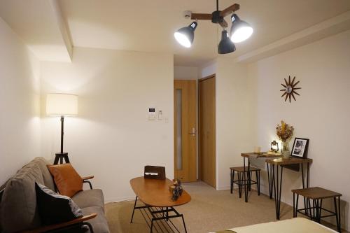 a living room with a couch and a table at Chuan House Nambaminami Hanazonocho in Osaka