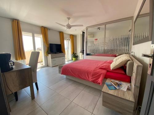 1 dormitorio con 1 cama grande de color rojo y escritorio en Charmante chambre avec vue mer, en La Ciotat