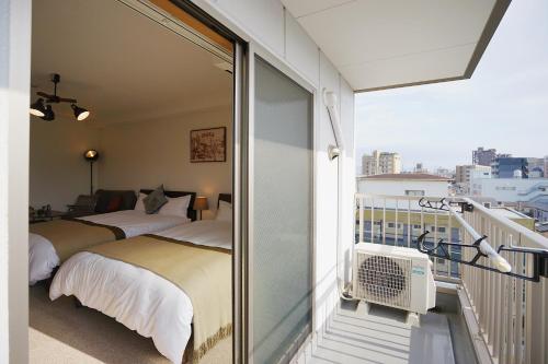 a bedroom with two beds on a balcony at Chuan House Nambaminami Hanazonocho in Osaka