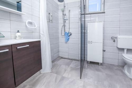 La salle de bains est pourvue d'une douche, d'un lavabo et de toilettes. dans l'établissement Apartments Juro, à Rogoznica