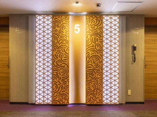 a hallway with a door with a gold and white patterned wall at Hotel Wing International Nagoya in Nagoya