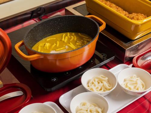 a pot of food on a stove with bowls of noodles at Hotel Wing International Nagoya in Nagoya