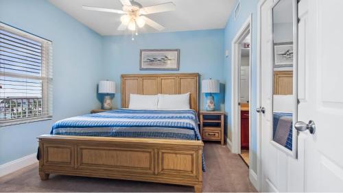 een blauwe slaapkamer met een bed en een plafondventilator bij Laketown Wharf #317 by Nautical Properties in Panama City Beach