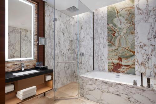a bathroom with a shower and a tub and a sink at Sheraton Beijing Lize Hotel in Beijing