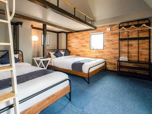 a bedroom with two bunk beds and a brick wall at Hotel Base Nara in Nara