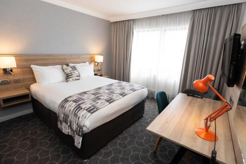 a hotel room with a bed and a desk and a television at Holiday Inn Preston by IHG in Preston