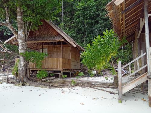 una casa de madera en la playa con un árbol en Yenrou Homestay, en Yennanas Besir