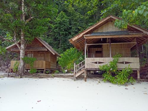 una casa sulla spiaggia vicino ad alcuni alberi di Yenrou Homestay a Yennanas Besir