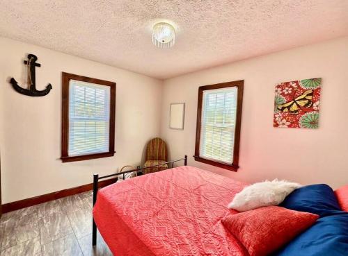 a bedroom with a red bed and two windows at Trestle Creeks Original Farmhouse in Bloomington