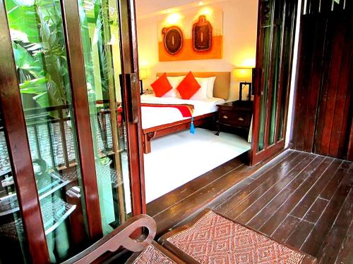a bedroom with a bed and a room with a window at Yantarasri Resort in Chiang Mai