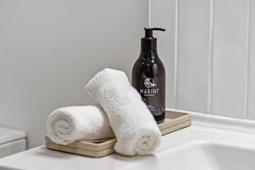 a bathroom with two towels and a bottle of soap at Te Karaka Lodge in Port Waikato