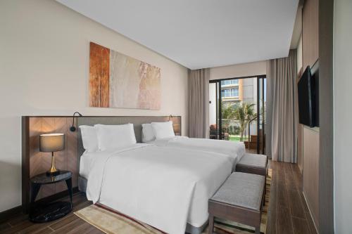 a bedroom with a large white bed and a window at Angsana Ho Tram in Ho Tram