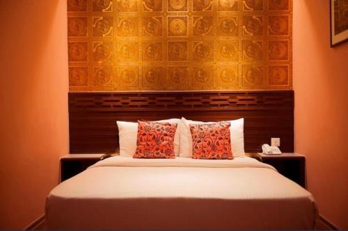 a bedroom with a bed with a large headboard and pillows at Apple Hotel Penang in George Town