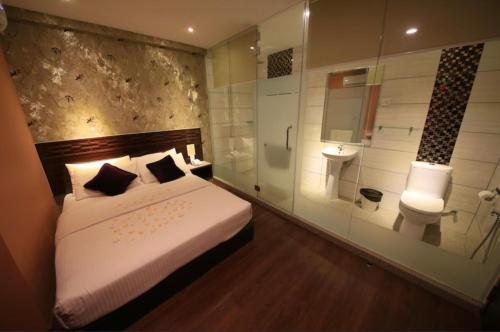 a bedroom with a bed and a bathroom with a shower at Apple Hotel Penang in George Town