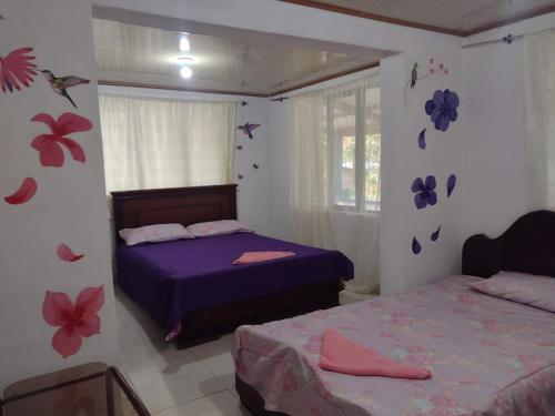 a bedroom with two beds and flowers on the wall at hostal Sueño Paraiso- Observatorio astronómico in Popayan