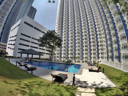 a large building with a swimming pool in front of a building at Chill Staycation at Grass Residences in Manila