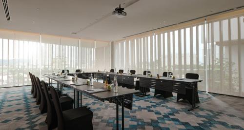 a conference room with long tables and chairs and windows at Amari SPICE Penang in Bayan Lepas
