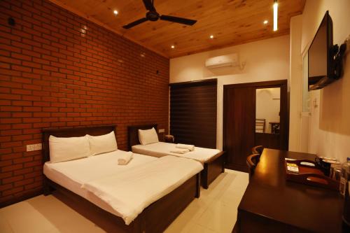 um quarto com 2 camas e uma parede de tijolos em J Hotel em Jaffna