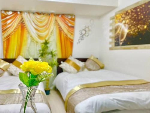 a bedroom with two beds and a vase with yellow flowers at *301 Oshiage sta 3mins walk! Wi-Fi Elevator in Tokyo