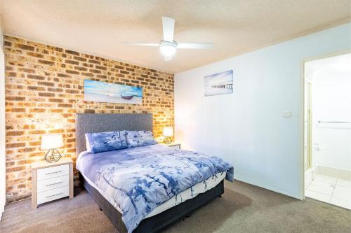 a bedroom with a bed and a brick wall at Bay Parklands 23 located at Little Beach with air con pool and tennis court in Shoal Bay