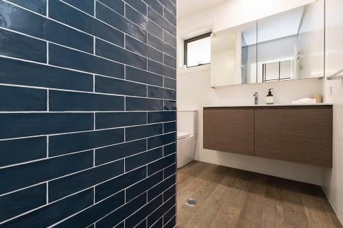 baño con pared de azulejos azules y lavamanos en Gunsynd Studio Apartment, en Scone