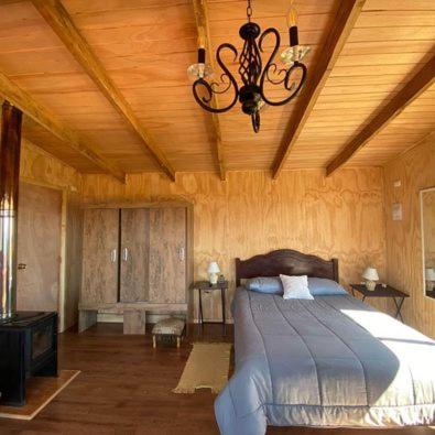 a bedroom with a bed and a chandelier at Lomas de Riñihue para 2p in Valdivia