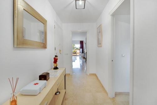 pasillo blanco con lavabo y espejo en Lujoso apartamento con alucinantes vistas al golf - Iwii A 38 en Marbella