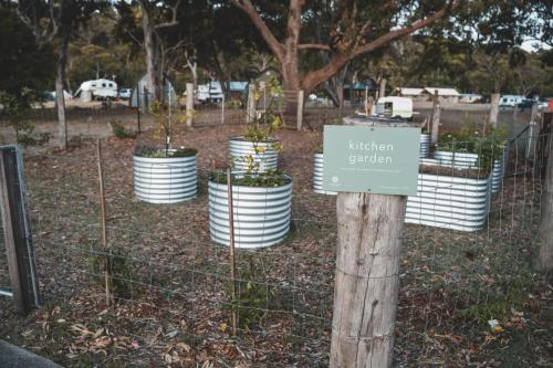 a sign on a fence with plants in pots at Tathra Beach Eco Camp in Tathra