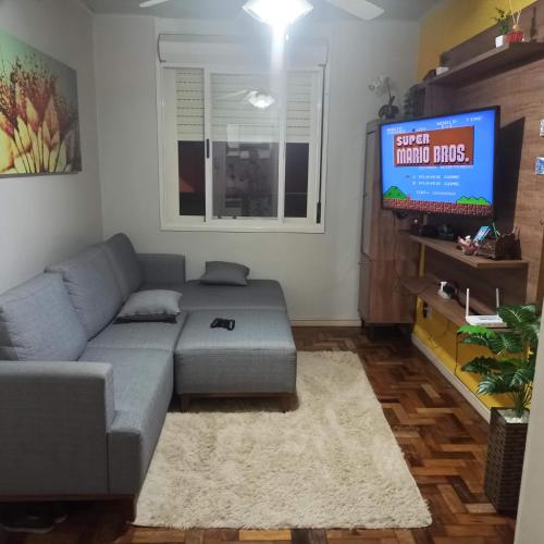 a living room with a couch and a flat screen tv at Amplo apt próximo ao Consulado in Porto Alegre