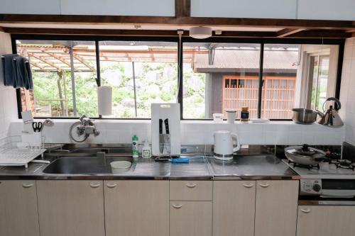 a kitchen with a sink and a counter top at 一軒家貸切 ARUYOguesthouse BBQと焚き火ができる宿 