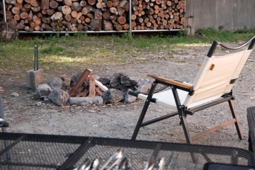 una silla sentada junto a un montón de troncos en 一軒家貸切 ARUYOguesthouse BBQと焚き火ができる宿 
