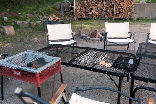 一軒家貸切 ARUYOguesthouse BBQと焚き火ができる宿 : طاولة مع شواية وكراسي ومدفأة