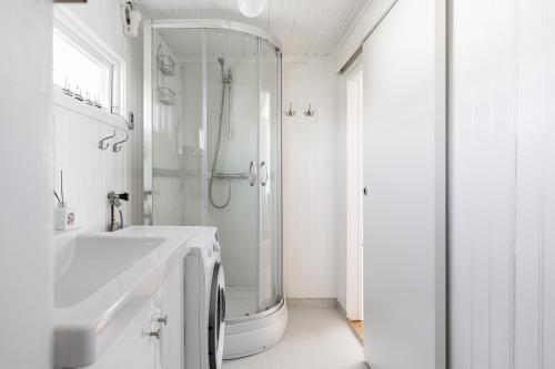 a white bathroom with a shower and a sink at Pleasant cottage on Oland with a panoramic view of Kalmarsund in Degerhamn