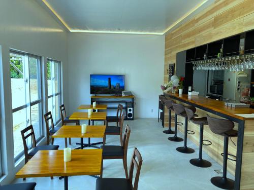 um restaurante com mesas e cadeiras de madeira e um bar em Nakijin Resort Guest House em Nakijin