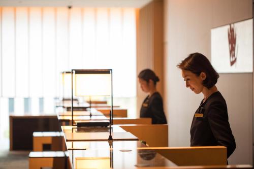 a woman standing in front of a desk with a laptop at The Capitol Hotel Tokyu in Tokyo