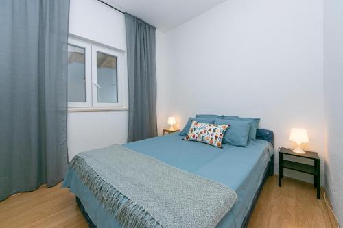 1 dormitorio con 1 cama azul y 2 ventanas en Apartments by the sea Pisak, Omis - 1008, en Mimice