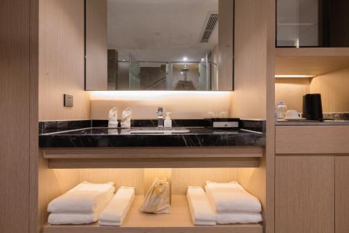 a bathroom with a sink and towels on a shelf at 义乌曼卡兰酒店国际商贸城店Yiwu kaiding Hotel in Yiwu