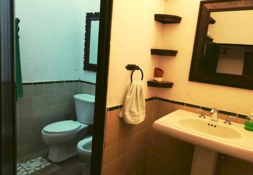bagno con servizi igienici, lavandino e specchio di Casa Romantica a Antigua Guatemala