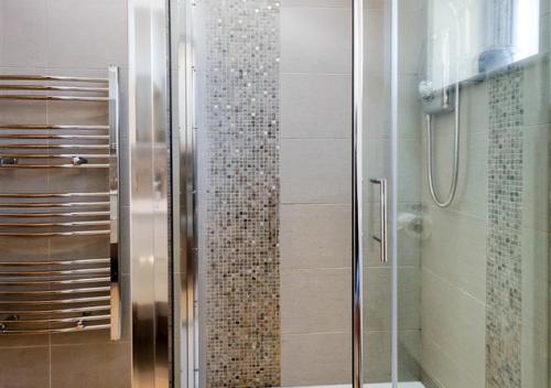 a bathroom with a shower with a glass door at Jennys Cottage in Abersoch