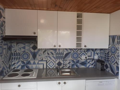 une cuisine avec des armoires blanches et un évier dans l'établissement Cantalaoude, à Soulac-sur-Mer