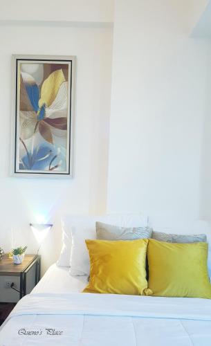 a bed with yellow pillows and a painting on the wall at Mactan Newtown - 1BR Stunning Ocean View and City View in Mactan